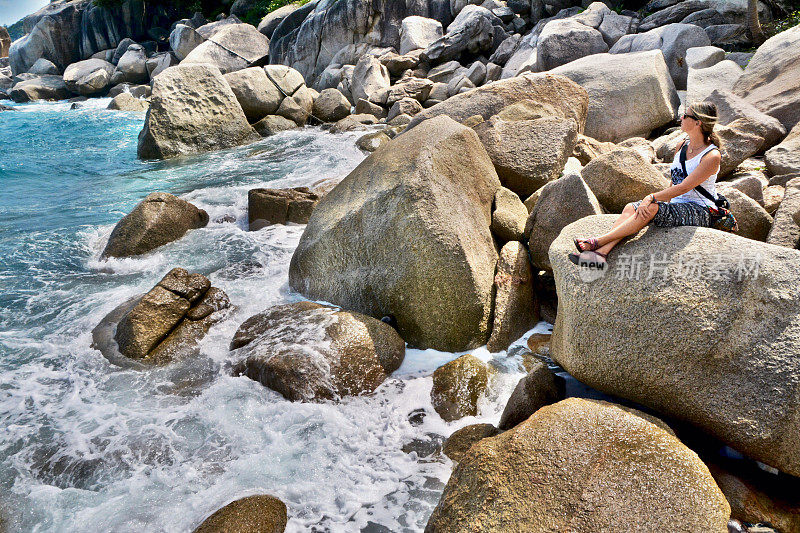 西方女人从旅游中放松下来，在泰国Ko Tao的岩石海岸享受海景